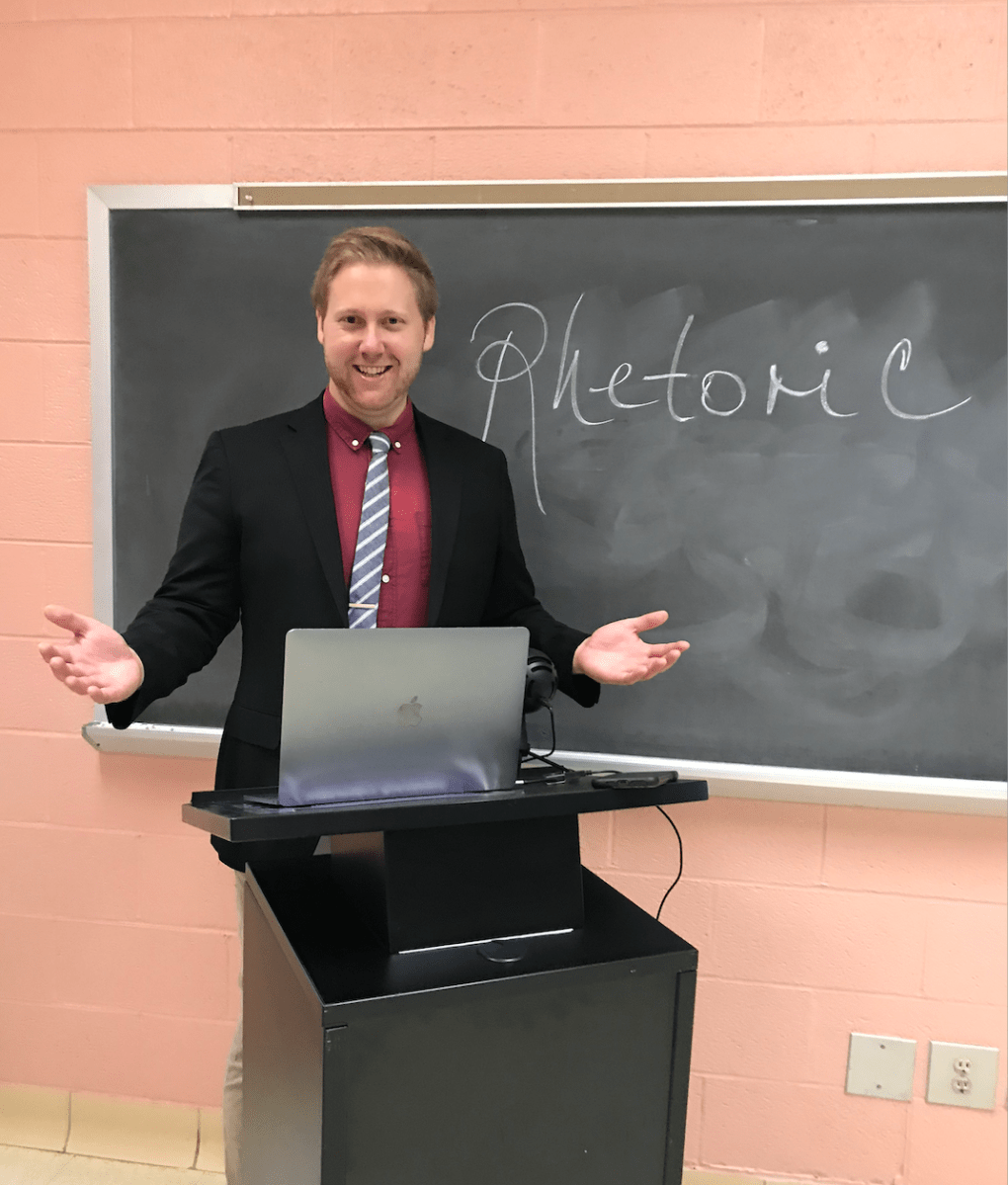 Jacob appears in front of a chalkboard reading "rhetoric"